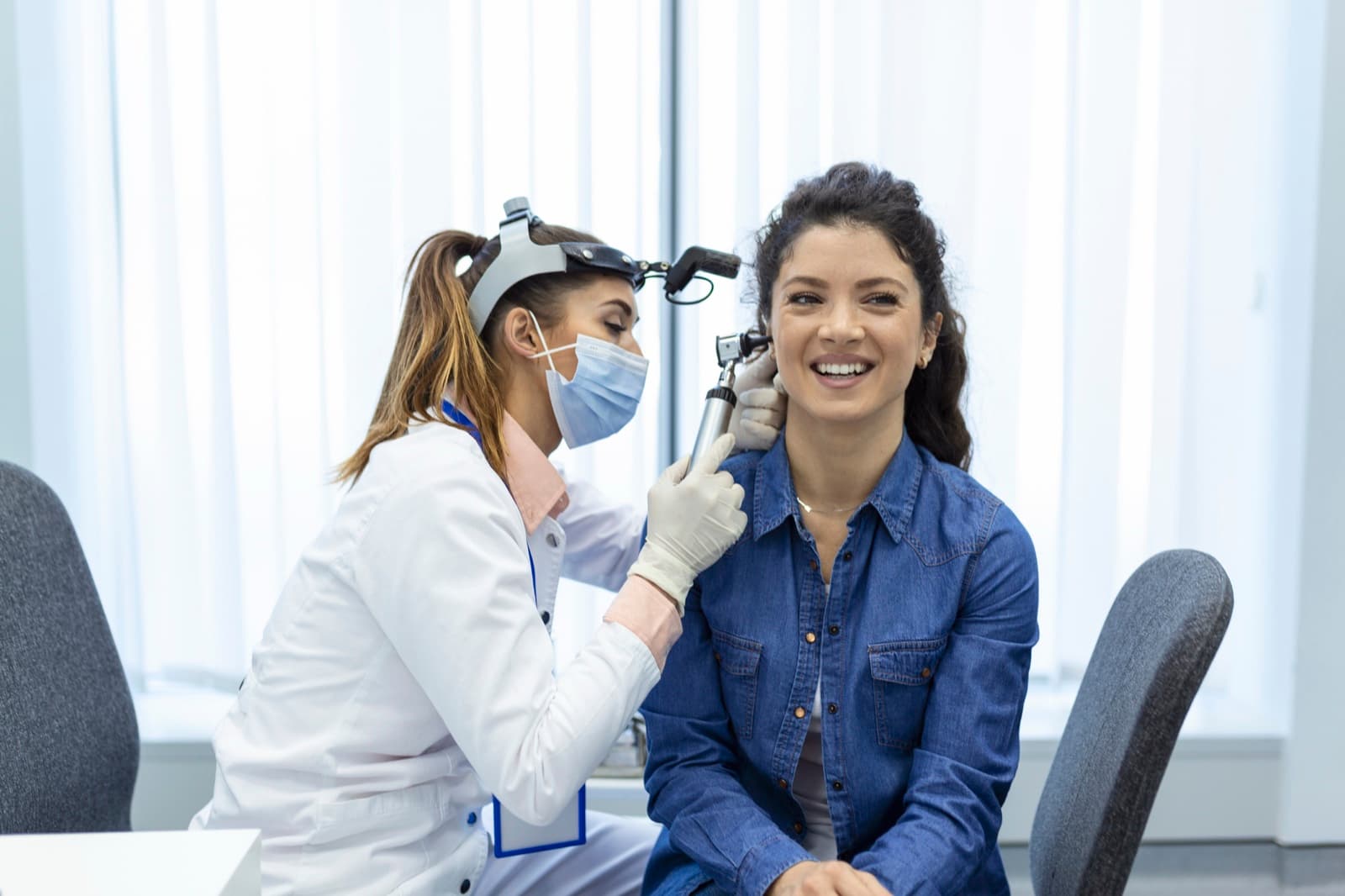 Une audioprothésiste examine l'oreille d'une patiente à l'otoscope